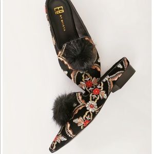 Velvet slides with colored embroidery and a puff